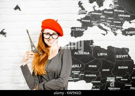 Femme debout avec eiffel tower près du mur avec carte du monde dans l'arrière-plan, rêver d'un voyage à Paris Banque D'Images