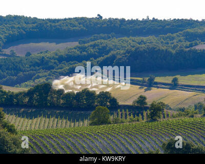 Les grandes cultures agricoles d'être arrosé de gicleurs dans le sud de la France de la brume sèche montrant vignes en premier plan Banque D'Images