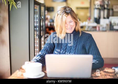 Happy woman using laptop avec tasse de café latte dans Banque D'Images