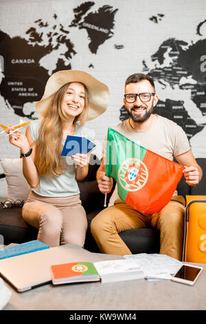 Jeune couple assis avec pavillon portugais et de passeport à l'agence de voyage bureau sur la carte du monde contexte prepairing pour un voyage au Portugal Banque D'Images