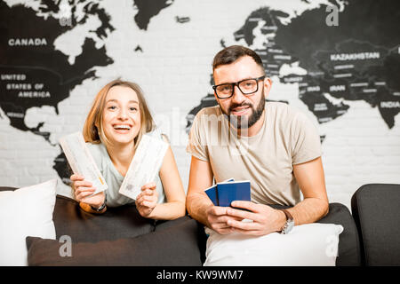 Portrait d'un jeune couple de voyageurs avec les billets et les passeports à l'intérieur sur la world map background Banque D'Images