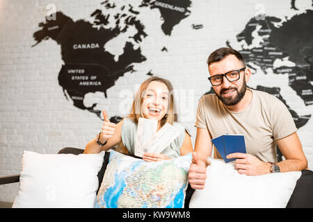 Portrait d'un jeune couple de voyageurs avec les billets et les passeports à l'intérieur sur la world map background Banque D'Images