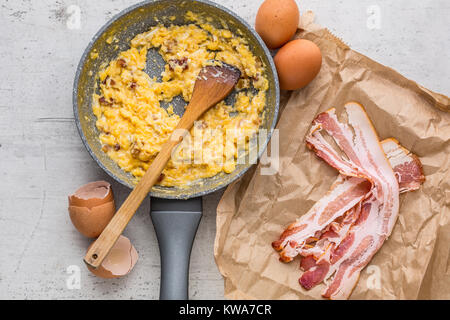 Du jambon et des œufs. Oeufs brouillés avec bacon dans pan en céramique. Banque D'Images