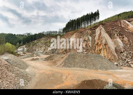 Une grande pierre pit dans les Ardennes, en Belgique avec des nuages sombres, un reste de forêt au sommet de la colline. Banque D'Images