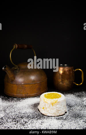Gâteau au citron avec du sucre en poudre sur fond sombre avec cuivre antique tea pot et mug Banque D'Images