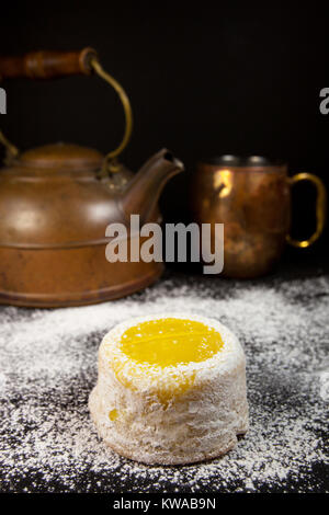Gâteau au citron avec du sucre en poudre sur fond sombre avec cuivre antique tea pot et mug Banque D'Images
