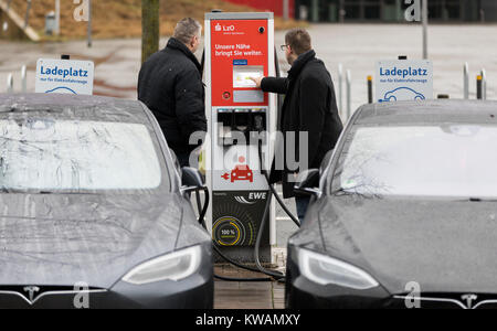 Deux hommes charger leurs voitures électriques sur le parking de la caisse d'épargne LzO (Oldenburg) siège à Oldenburg, Allemagne, 31 décembre 2017. Photo : afp/Assanimoghaddam Mohssen Banque D'Images