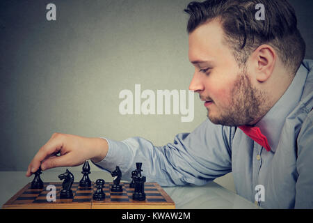Jeune homme chunky concentrés sur la stratégie de construction tout en jouant aux échecs. Banque D'Images
