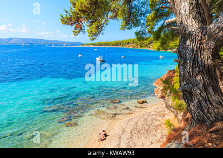 Couple non identifié de personnes assises sur la plage près de la célèbre plage de Zlatni Rat à Bol Cape town, île de Brac, Croatie Banque D'Images