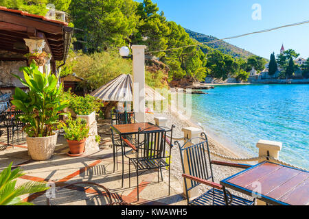 Table avec chaises de petit restaurant sur la plage dans la ville de Bol, Île de Brac, Croatie Banque D'Images