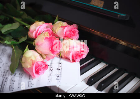 Un bouquet de roses roses et des notes sur le clavier du piano. Le concept de l'éducation musicale et de concerts. Banque D'Images