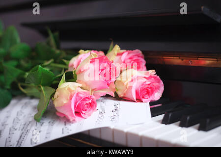 Un bouquet de roses roses et des notes sur le clavier du piano. Le concept de l'éducation musicale et de concerts. Banque D'Images