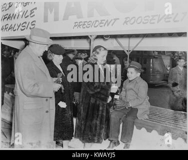 Margaret Truman, fille du président Harry Truman et la Première Dame Bess Truman, gouttes une pièce de monnaie dans une bouteille tenue par un jeune garçon lors d'une apparition publique de la March of Dimes, le 14 janvier 1946. Banque D'Images