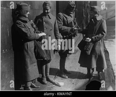 Vêtus de manteaux de laine longue et de chapeaux, deux femmes volontaires pour l'Armée du Salut, dite de "donut lassies ', distribuer des beignes à deux soldats américains Africains renvoyés de l'Artillerie de Campagne 351, Louisville, Kentucky, 1919. L'image de courtoisie des Archives nationales. Banque D'Images