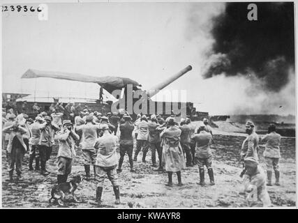Sur les champs de bataille pendant la Première Guerre mondiale, un grand canon français se décharge et lance un shell à l'ennemi allemand, tandis que plusieurs des artilleurs se tenir autour d'essayer de protéger leurs oreilles, le son à partir de 1918. L'image de courtoisie des Archives nationales. Banque D'Images