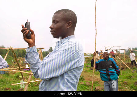 Cyuve, camp de réfugiés du Rwanda, de l'éruption du volcan Nyriragongo le 18 Jan 2002 dans les environs de Goma en RDC. Un visiteur au camp effectue un appel sur son mobile. Banque D'Images