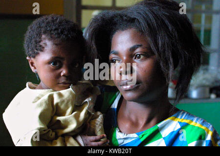 Camp d'Ibanda, à Bukavu, à l'emplacement d'un ancien centre de formation du corps de la paix, pour les personnes déplacées de Goma par la coulée de lave après une éruption volcanique, Jan 2002. Veronica Kibonge, 20, avec sa fille, Florence, 1 ans. Banque D'Images