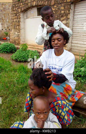 Camp d'Ibanda, à Bukavu, à l'emplacement d'un ancien centre de formation du corps de la paix, pour les personnes déplacées de Goma par la coulée de lave après une éruption volcanique, Jan 2002 ici les membres de la famille chaque tresse les cheveux. Banque D'Images