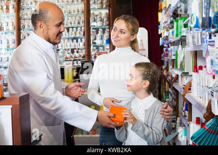 Pharmacien principal debout avec une caisse dans la pharmacie et l'aide aux clients Banque D'Images