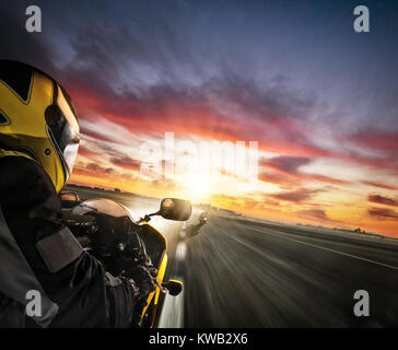 Deux coureurs de moto en direction de la ville. Concept de la vitesse de translation et la liberté. Beau ciel coucher de soleil spectaculaire. Banque D'Images