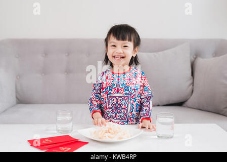 Petite fille vietnamienne en ao Dai, robe traditionnelle fêter le nouvel an à la maison. Du Têt. Banque D'Images