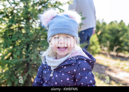 Gros plan du happy little girl having fun trouver un arbre de noël en Hiver Banque D'Images