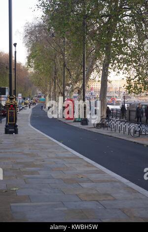 Piste cyclable le long de Joseph Bazalgette's Victoria Embankment, City of Westminster, Londres. Bordée d'arbres Téléphone rouge fort. Royaume-uni, Décembre, 2017. Banque D'Images