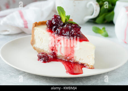 Gâteau au fromage avec sauce aux canneberges et feuille de menthe sur plaque blanche. Délicieux Gâteau au fromage de New York avec sauce aux baies Banque D'Images