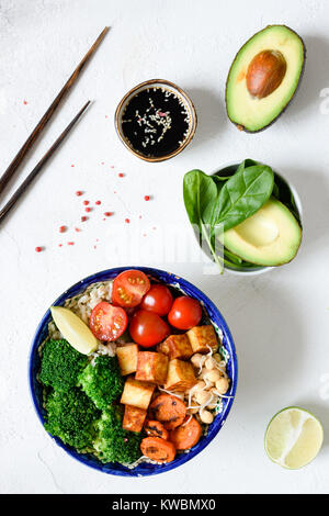 Bol Bouddha avec poivrons Carottes, avocat, tomate, brocoli, les choux de Bruxelles et tofu au fromage. Bol végétarien. Vue de dessus sur fond blanc en béton Banque D'Images