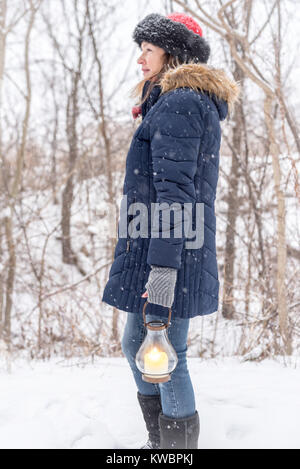 Femme pour profiter de la beauté de la neige fraîche sur le chemin boisé holding lantern Banque D'Images