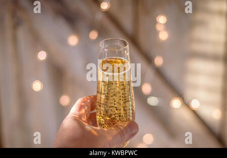 Part à la collecte d'un verre de champagne pour un toast avec lumières en arrière-plan Banque D'Images