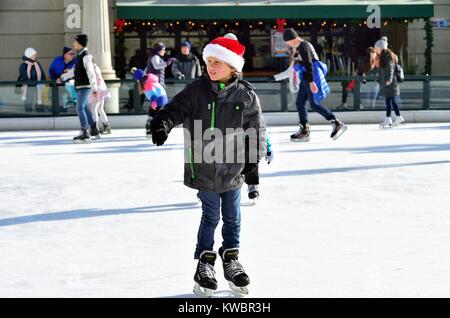Un jeune garçon, habillé pour la saison, parmi les patineurs profiter de la patinoire à la Chicago Millennium Park avant Noël. Chicago, Illinois, USA. Banque D'Images
