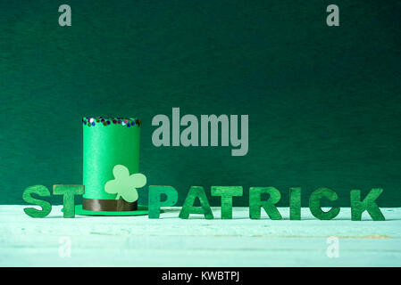 Lutin vert chapeau papier avec un trèfle et la St Patrick paroles écrites en lettres en bois vert, sur un fond de bois avec de l'espace pour le texte. Banque D'Images