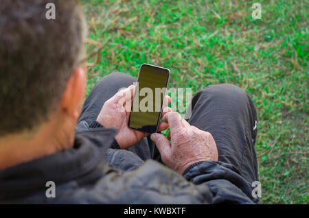 Close up d'un doigt ridé touchant un smartphone, vieil homme utilise la technologie. Internet. Banque D'Images