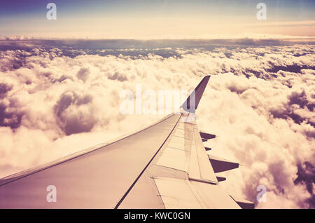 Une aile d'avion au-dessus des nuages vus à travers une fenêtre d'un aéronef, couleur tonique travel concept photo. Banque D'Images