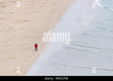 Un homme mûr vu de loin marcher le long du rivage sur plage de Crantock Newquay Cornwall. Banque D'Images