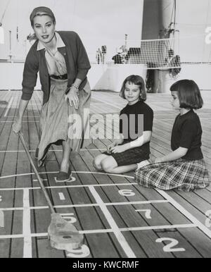 Grace Kelly en jouant le jeu de palets sur le pont de l'USS Constitution, le 10 avril 1956. Le navire a été arrêté à Algeciras, Espagne, sur ce chemin à Monaco où elle se maria au Prince Rainier III le 18 avril. Avec elle sont ses nièces, Margaret et Mary Lee Davis. - BSLOC  2015 (1 19) Banque D'Images