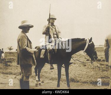 Theodore Roosevelt à cheval et tenant un fusil lors de son safari. Debout près de lui, c'est son fils Kermit, qui était le photographe officiel de la Smithsonian-Roosevelt de l'expédition d'Afrique, juin 1909 à mars 1910, dans l'Afrique de l'est britannique, Congo belge, et au Soudan (BSLOC 2017 8 4) Banque D'Images