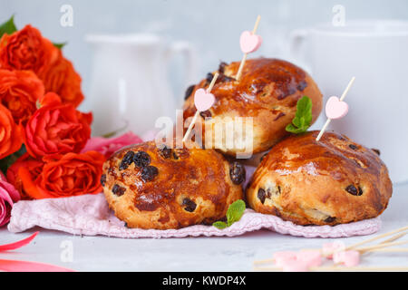 Le petit déjeuner pour la Saint-Valentin. Petits pains aux raisins secs, de beurre et de miel, un bouquet de fleurs. Banque D'Images