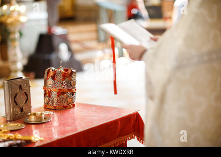 Mariage à l'église couronnes à la table avec croix et verre de vigne. Banque D'Images