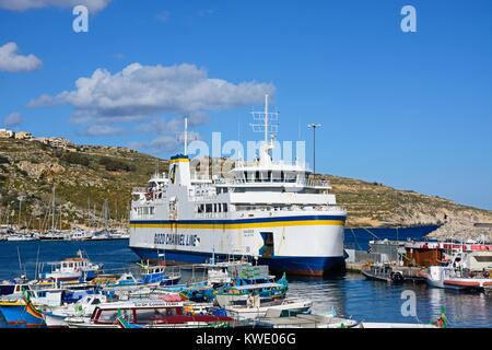 Bateau de pêche colorés amarrés dans le port avec le Gozo ferry amarré dans le port à l'arrière, Mgarr, Gozo, Malte, l'Europe. Banque D'Images