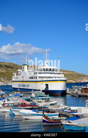 Les bateaux de pêche amarrés dans le port avec le Gozo ferry amarré dans le port à l'arrière, Mgarr, Gozo, Malte, l'Europe. Banque D'Images