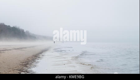 Une scène froide sur une plage de Jurmala avec peu de gens chiffres dans le brouillard et la distance de roulement de la mer. Banque D'Images