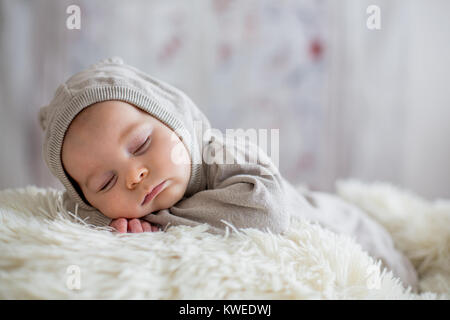 Sweet baby boy dans l'ensemble de l'ours, dormir dans le lit avec ours en peluche peluches, paysage d'hiver derrière lui Banque D'Images