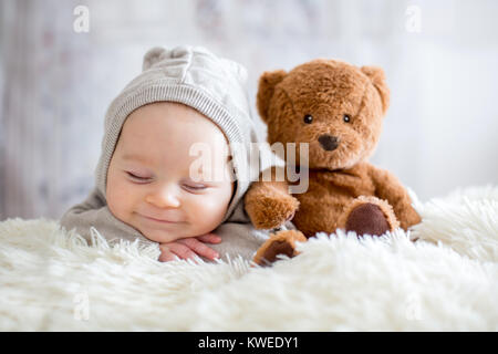 Sweet baby boy dans l'ensemble de l'ours, dormir dans le lit avec ours en peluche peluches, paysage d'hiver derrière lui Banque D'Images