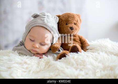 Sweet baby boy dans l'ensemble de l'ours, dormir dans le lit avec ours en peluche peluches, paysage d'hiver derrière lui Banque D'Images