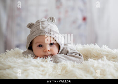 Sweet baby boy dans l'ensemble de l'ours, dormir dans le lit avec ours en peluche peluches, paysage d'hiver derrière lui Banque D'Images