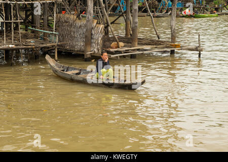 Une femme cambodgienne asiatique assis dans un canot en bois en attente sur l'eau du lac Tonlé Sap, de la plaine près de Kampong Phluk, le Cambodge, l'Asie du Sud Est. Banque D'Images