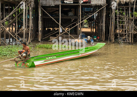 Une asiatique cambodgienne musculaire homme marchant dans la plaine du Grand Lac Tonlé Sap, à côté de l'eau marron powered moteur bateau vert longue et fine, le Cambodge au sud-est Banque D'Images