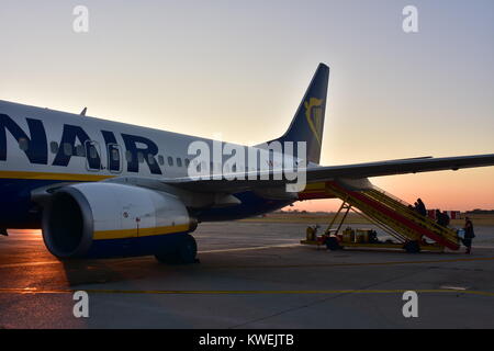 Les passagers d'avion Ryanair stationnés sur la piste en béton au lever du soleil. Banque D'Images